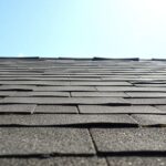 Cracked, buckling roof shingles under intense sun.