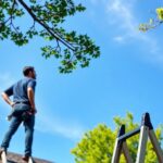 Man on ladder, inspecting roof.